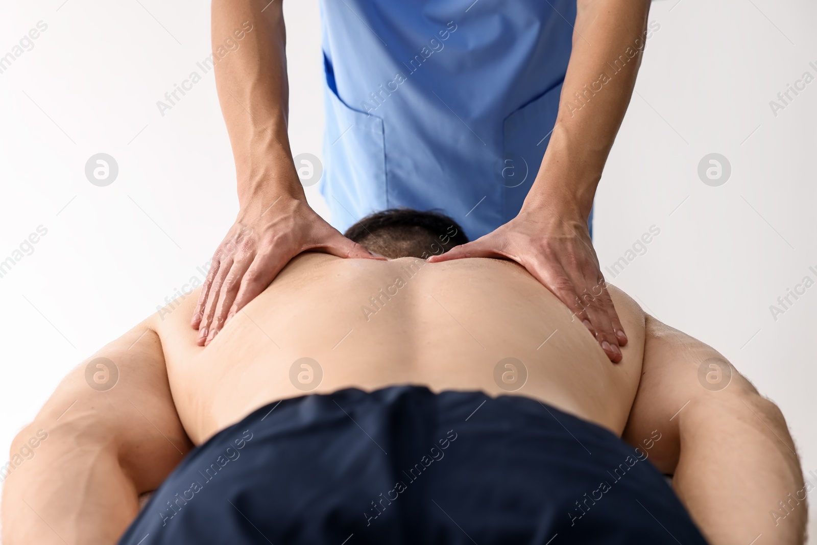 Photo of Professional physiotherapist doing back massage for his client indoors, closeup