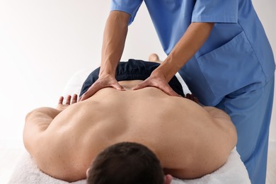 Photo of Professional physiotherapist doing back massage for his client indoors, closeup