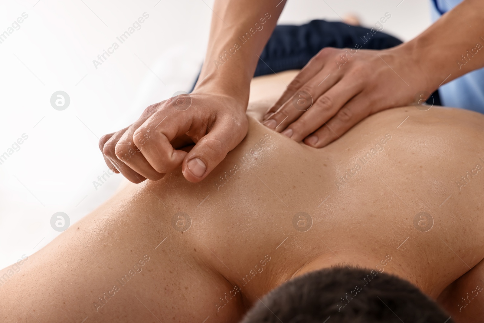 Photo of Professional physiotherapist doing back massage for his client indoors, closeup