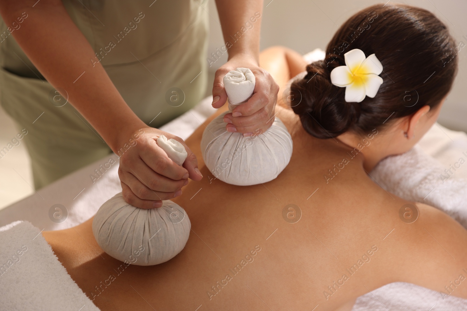 Photo of Woman receiving back massage with herbal bags in spa salon