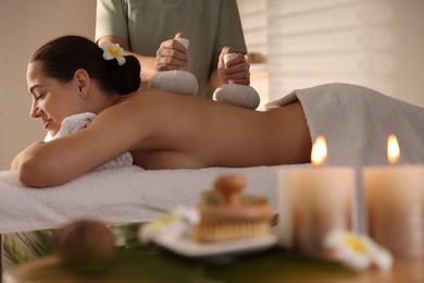 Photo of Woman receiving back massage with herbal bags in spa salon