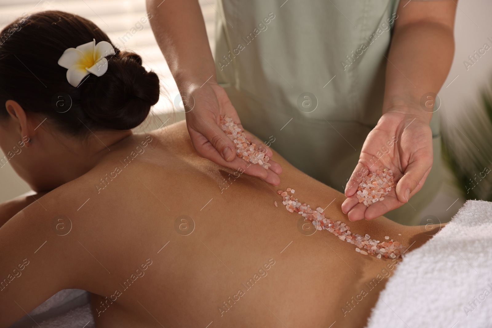 Photo of Woman receiving massage with sea salt in spa salon