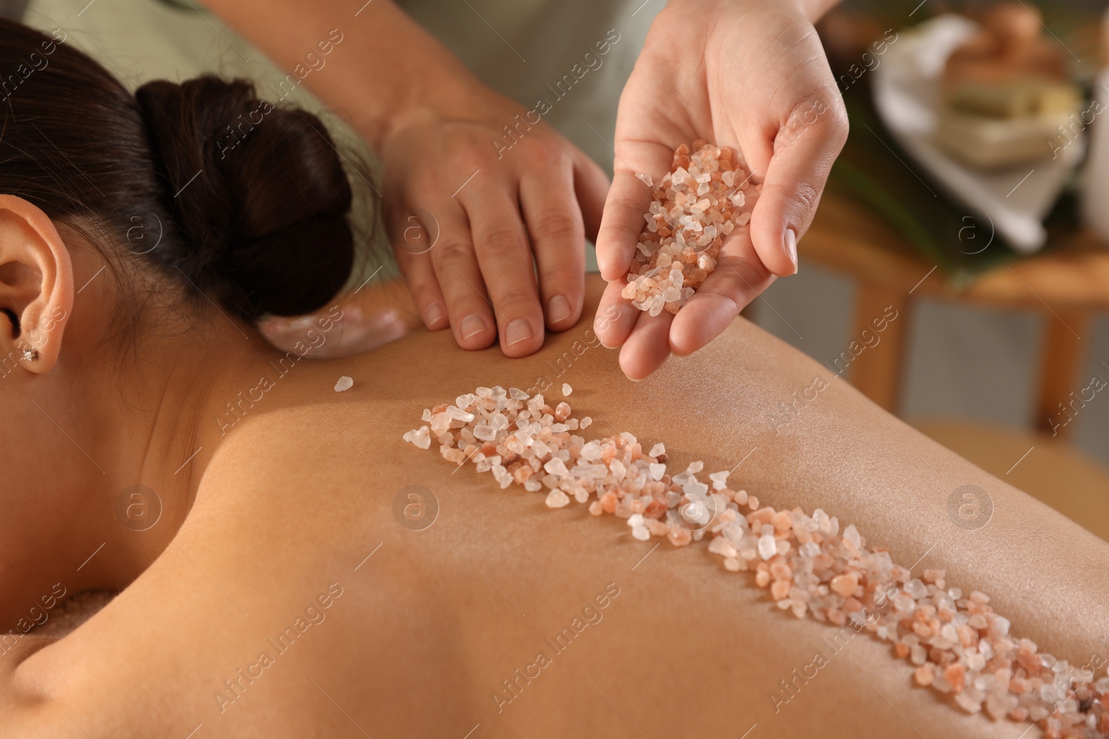 Photo of Woman receiving massage with sea salt in spa salon, closeup