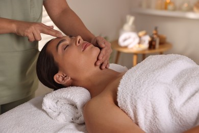 Woman receiving face massage in spa salon