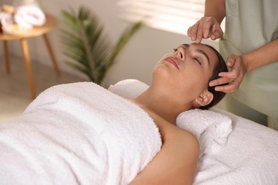 Woman receiving face massage in spa salon