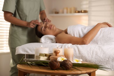 Woman receiving face massage in salon, focus on spa supplies