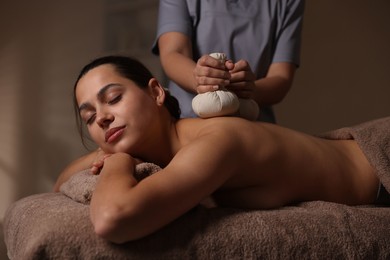 Woman receiving back massage with herbal bags in spa salon