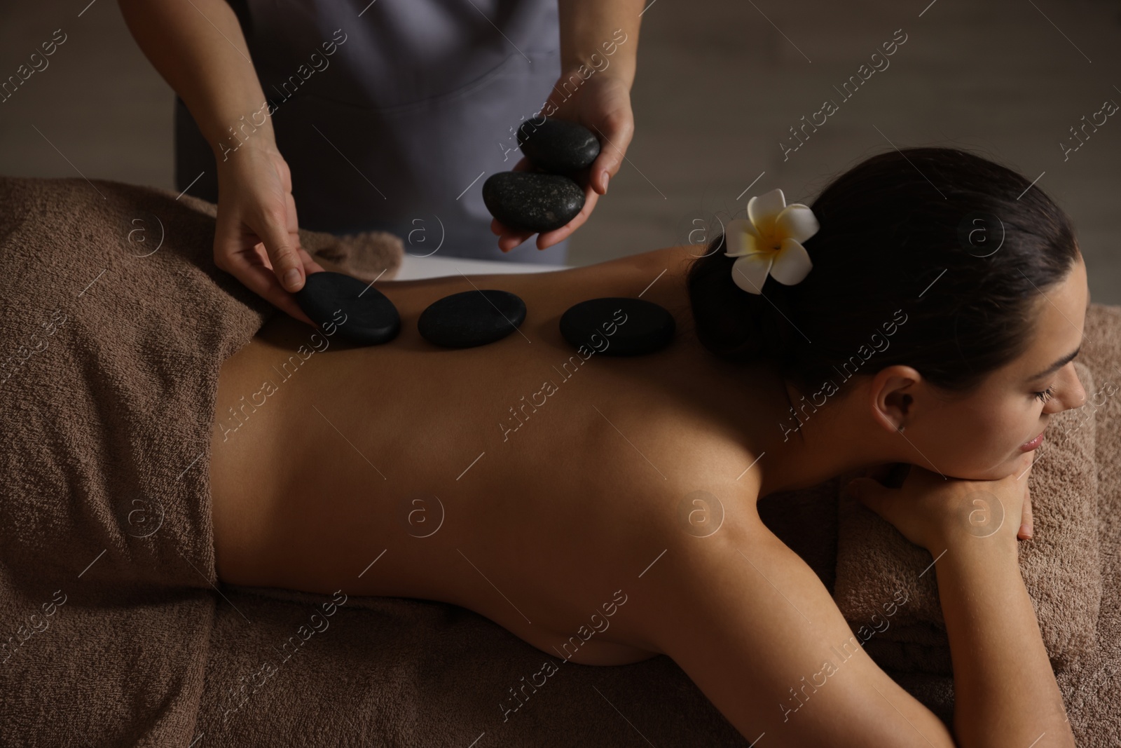 Photo of Woman receiving hot stone massage in spa salon