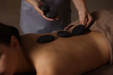 Woman receiving hot stone massage in spa salon, closeup