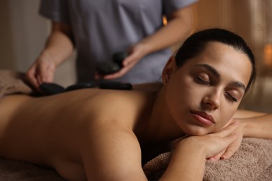 Photo of Woman receiving hot stone massage in spa salon