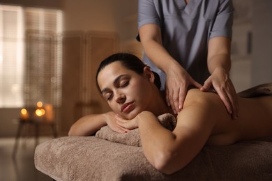 Woman receiving back massage in spa salon