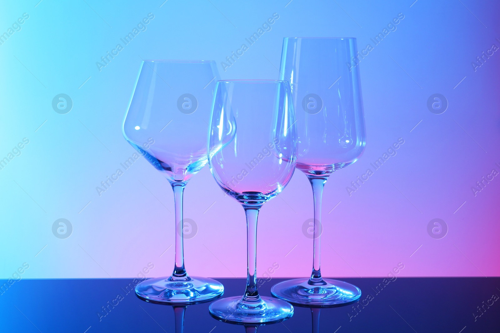 Photo of Empty glasses on table against color background