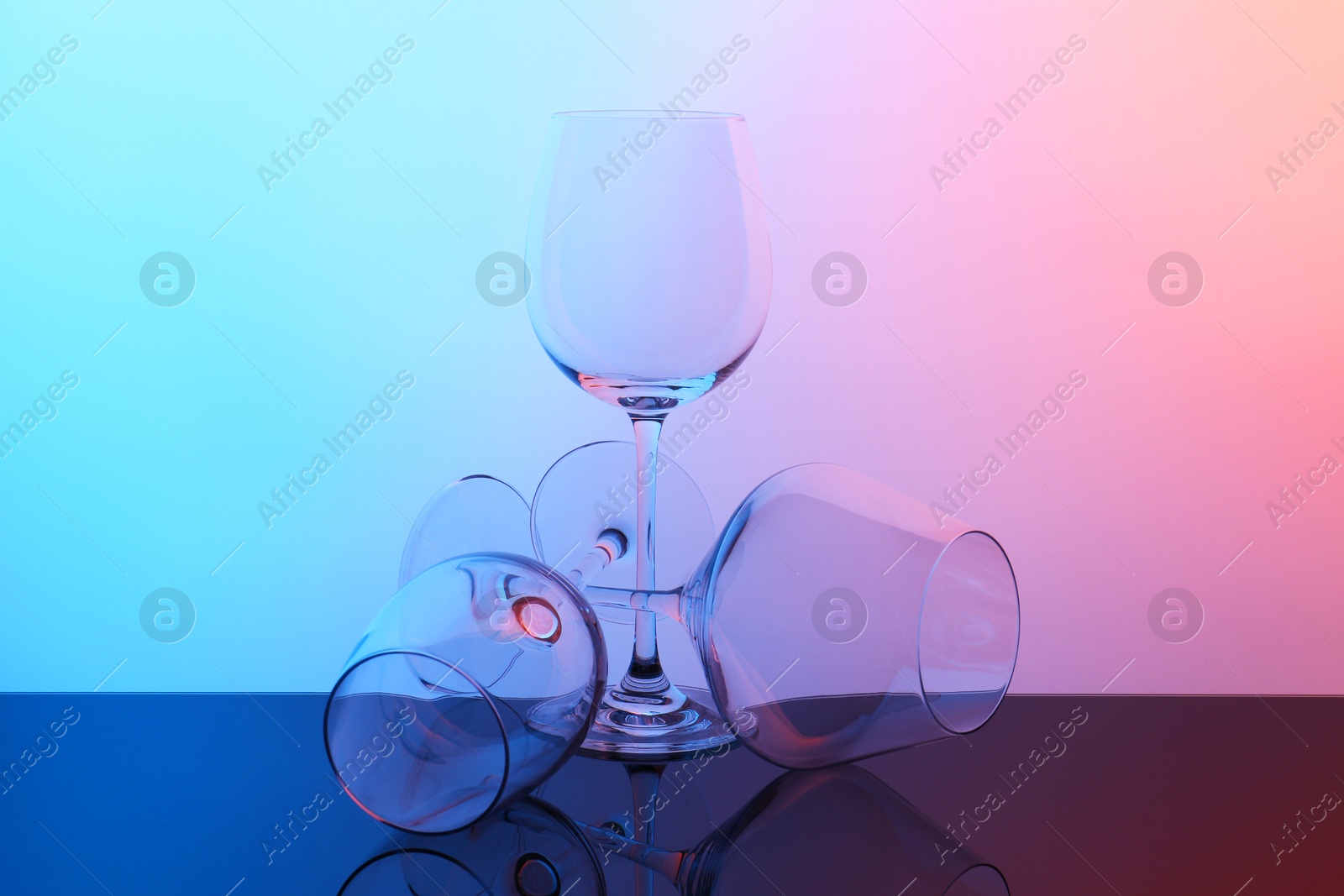 Photo of Empty glasses on table against color background