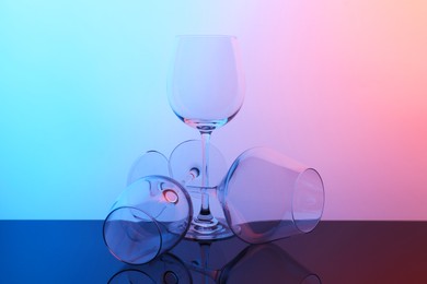 Photo of Empty glasses on table against color background