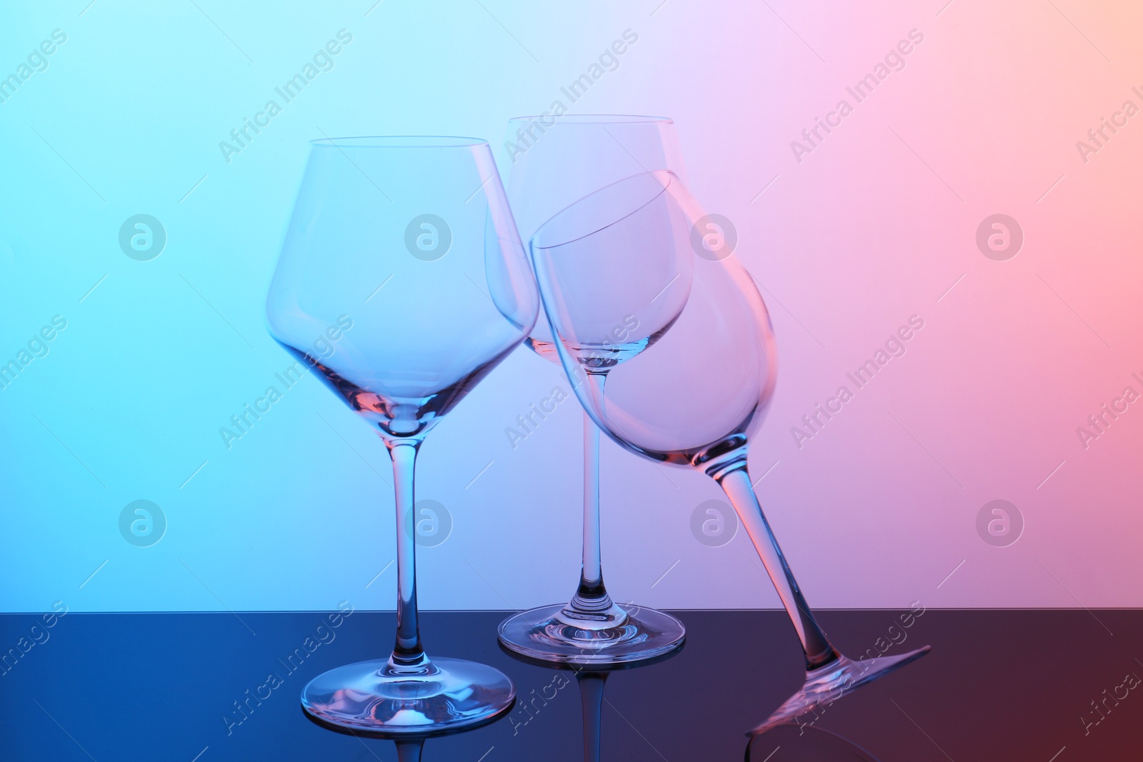 Photo of Empty glasses on table against color background