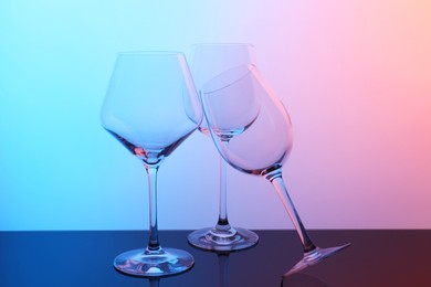 Photo of Empty glasses on table against color background