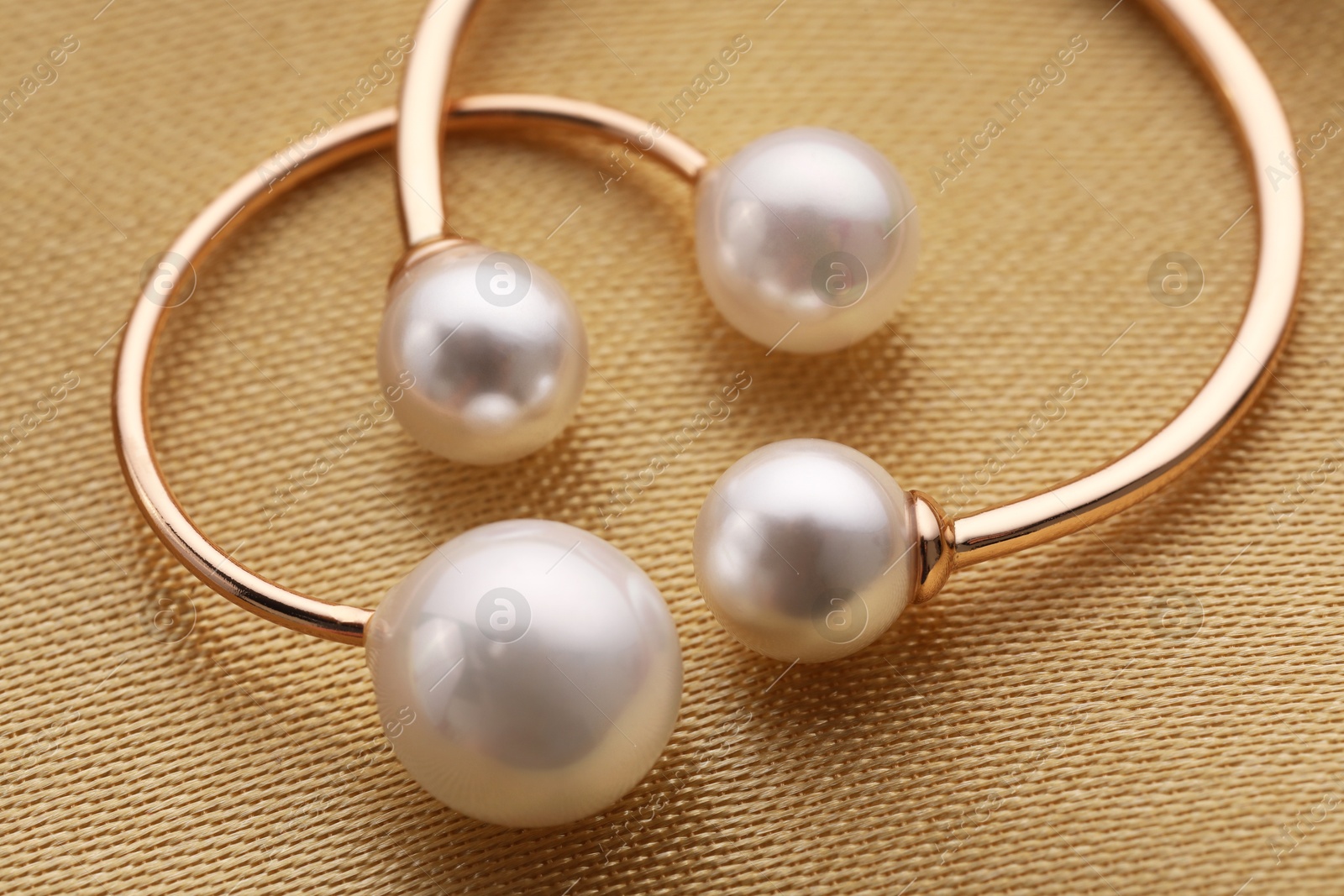 Photo of Beautiful pearl jewelry on golden silk, macro view