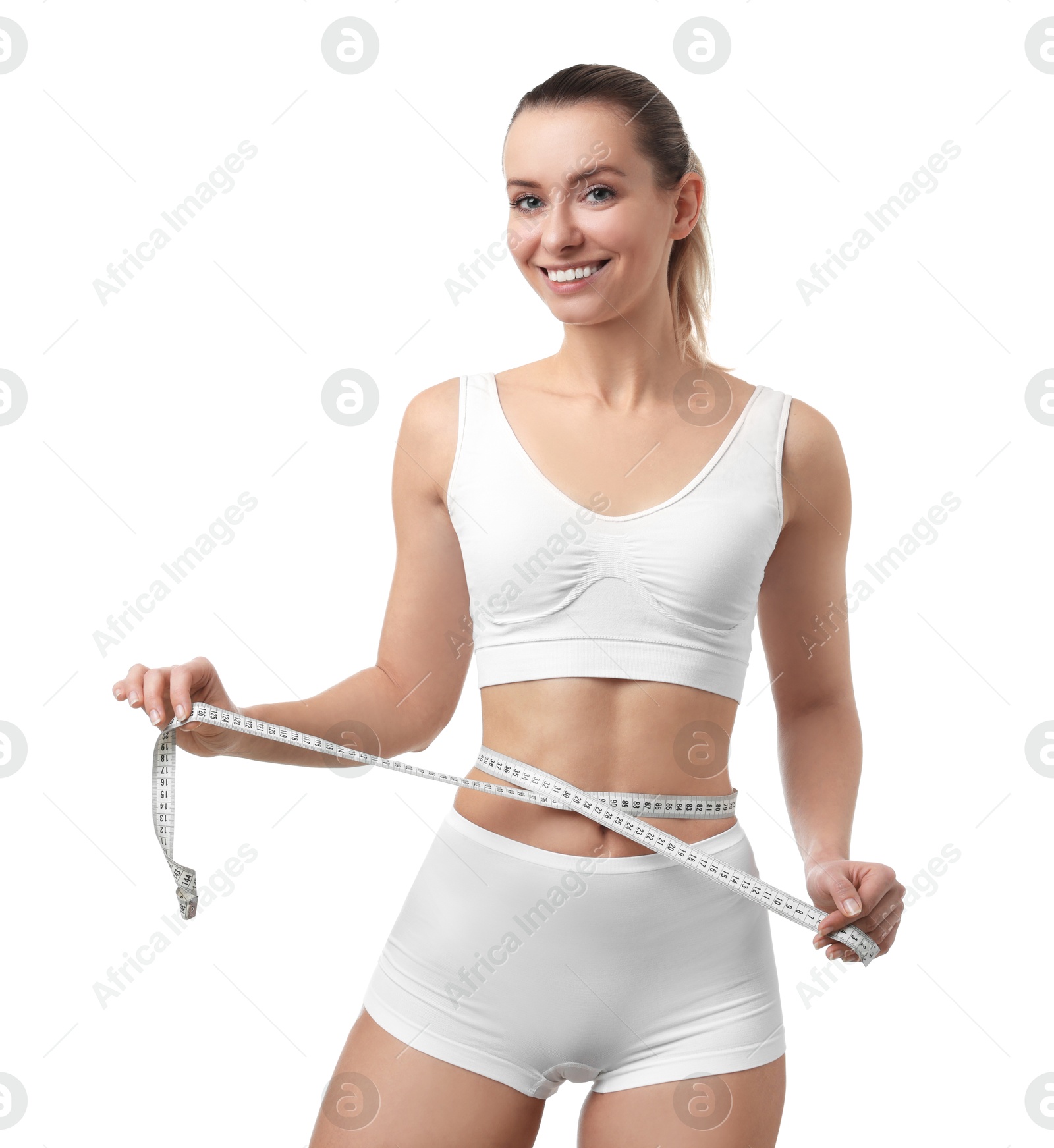 Photo of Weight loss. Happy woman measuring her slim waist with tape on white background