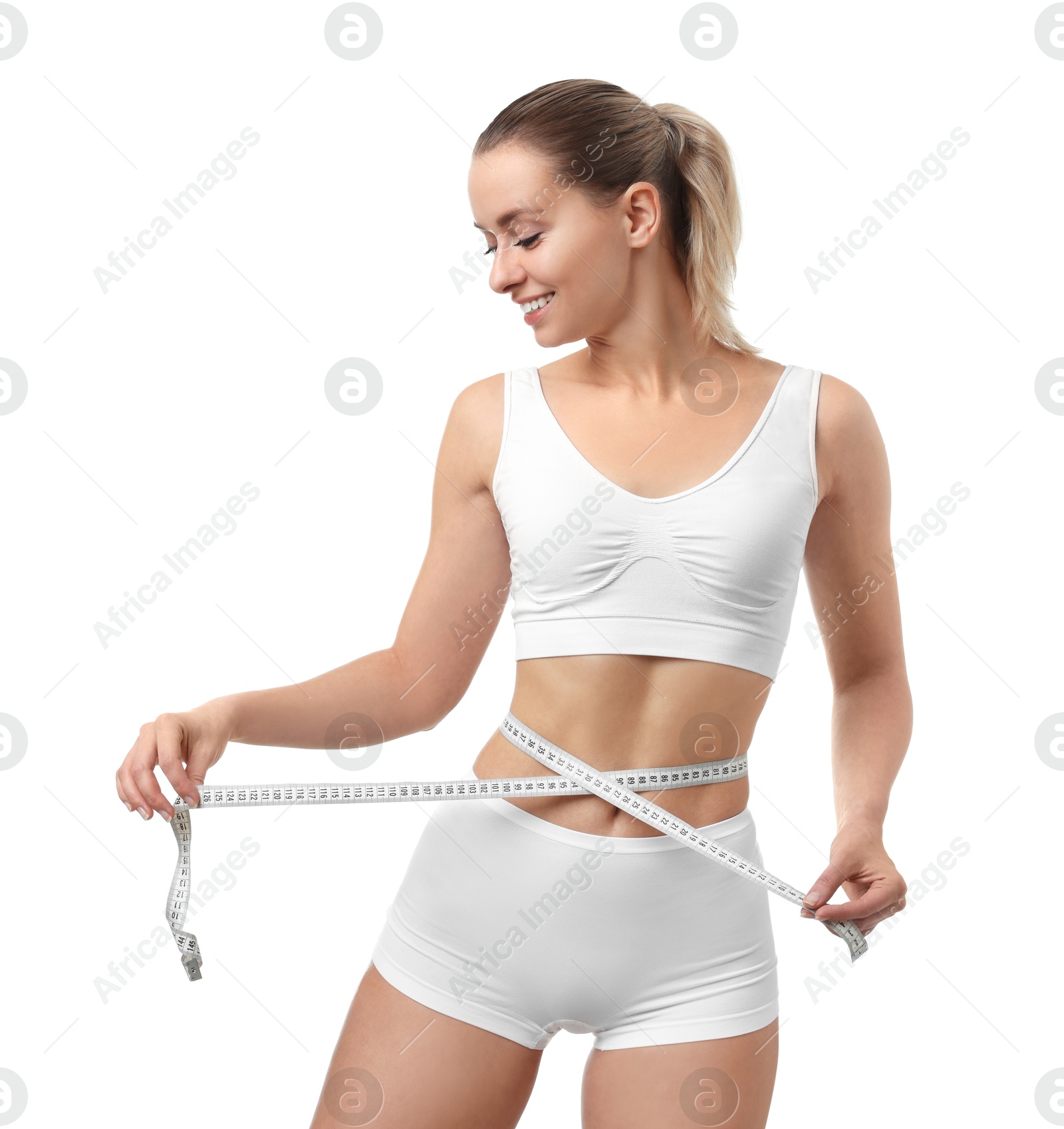 Photo of Weight loss. Happy woman measuring her slim waist with tape on white background