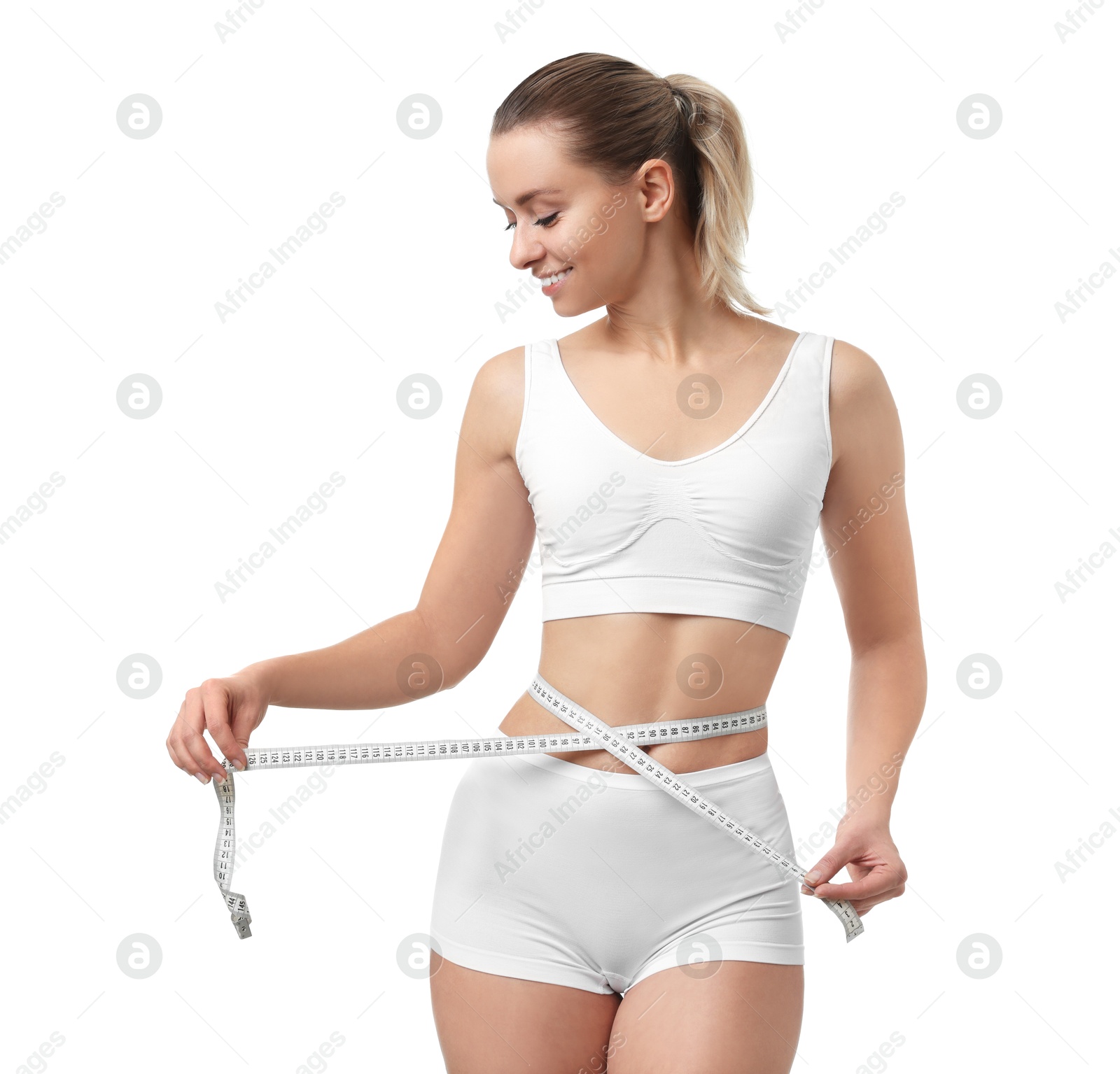 Photo of Weight loss. Happy woman measuring her slim waist with tape on white background