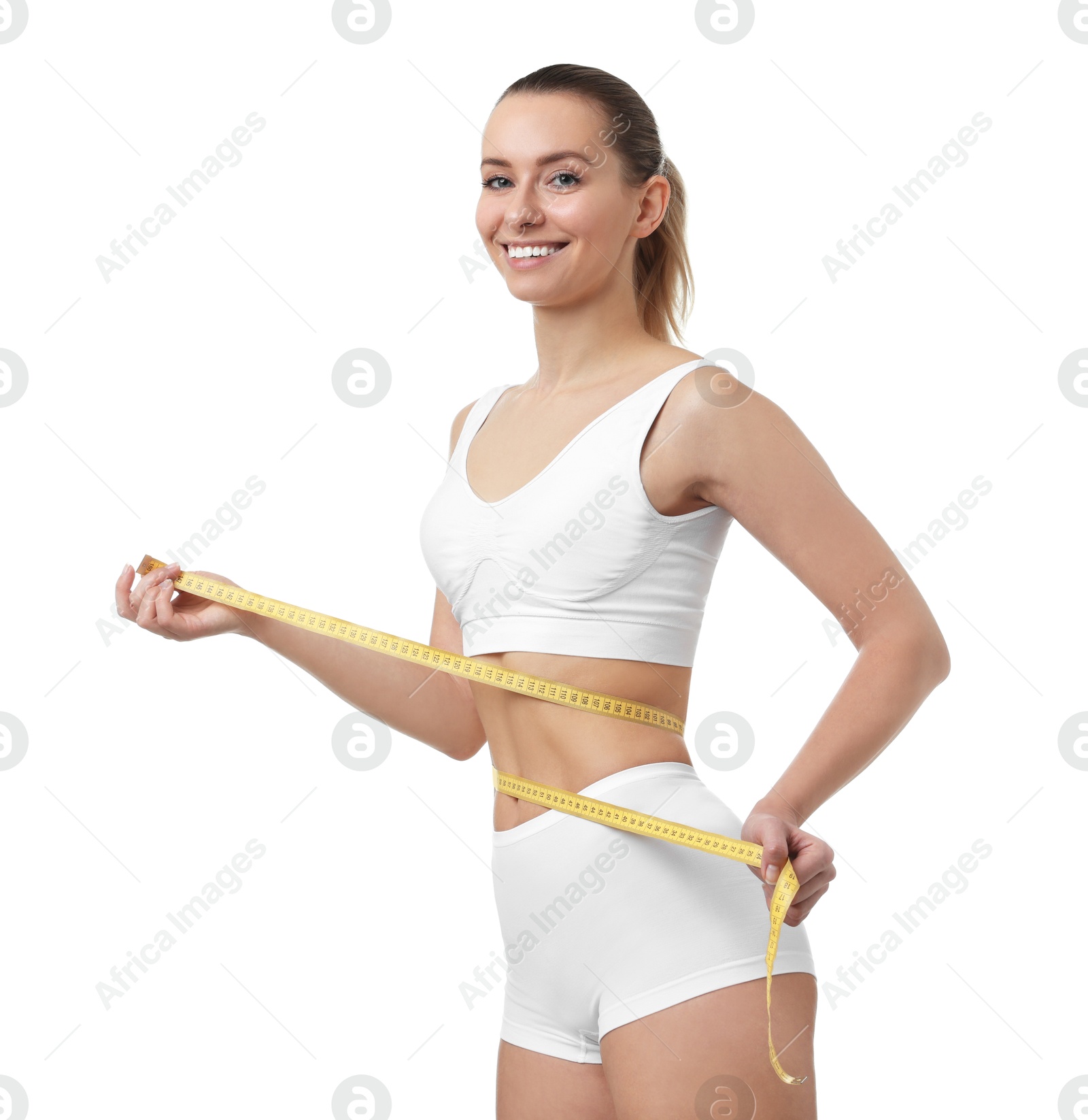 Photo of Weight loss. Happy woman measuring her slim waist with tape on white background