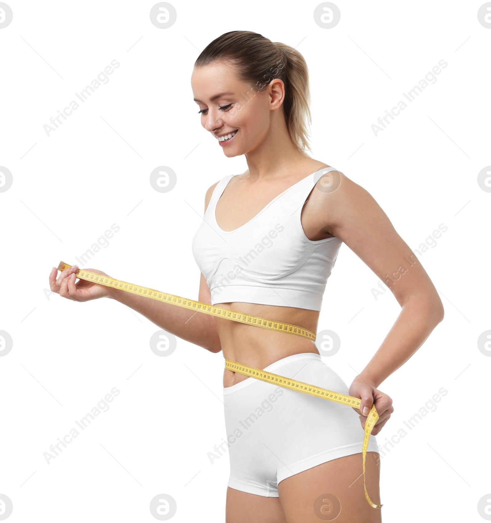 Photo of Weight loss. Happy woman measuring her slim waist with tape on white background