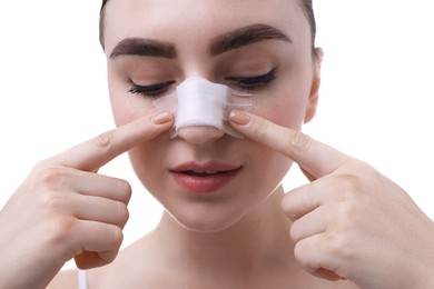 Photo of Woman with medical bandage on her nose after plastic surgery operation against white background