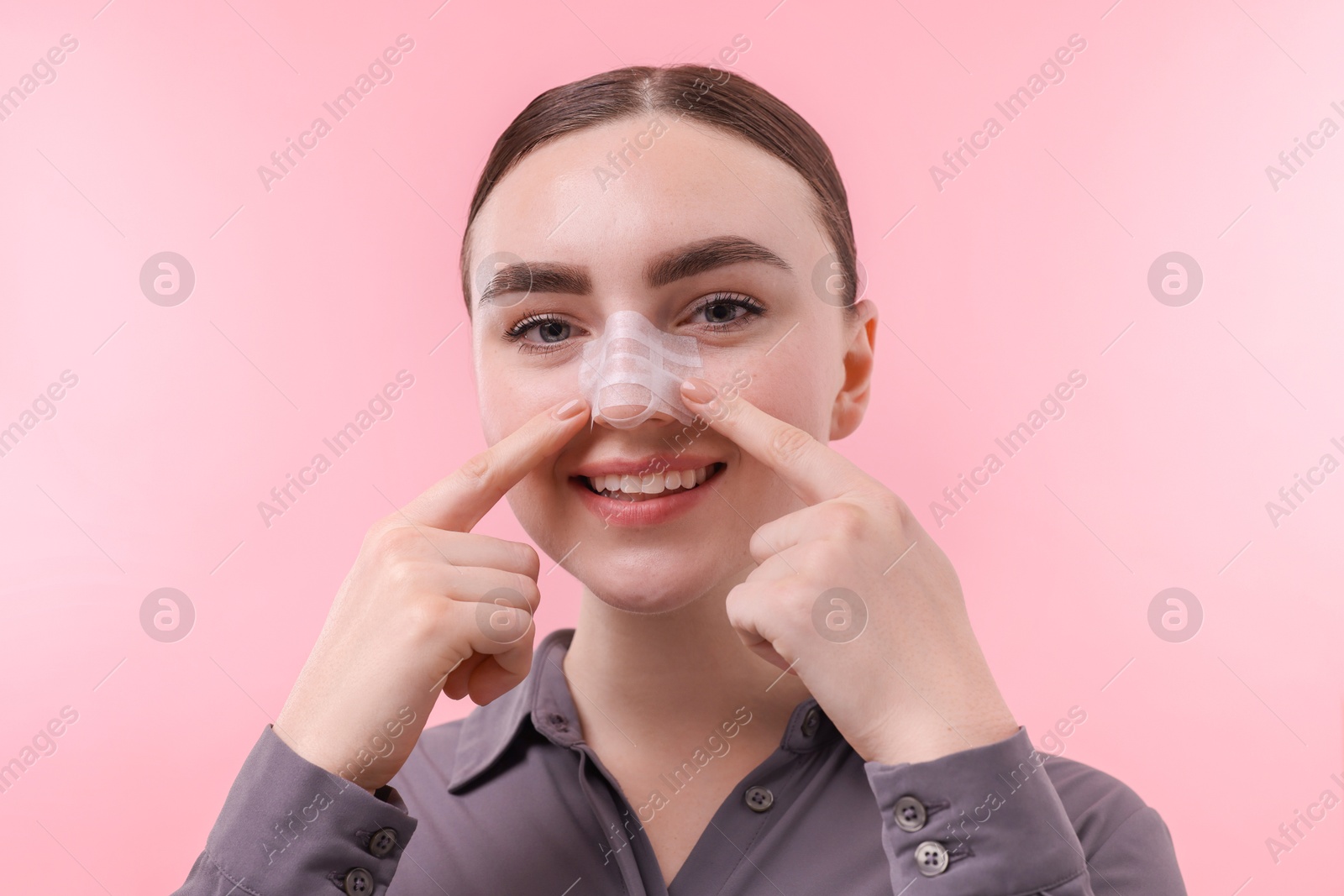 Photo of Woman with medical bandage on her nose after plastic surgery operation against pink background