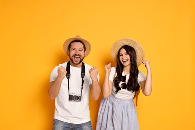 Tourism. Emotional couple in hats with camera on yellow background