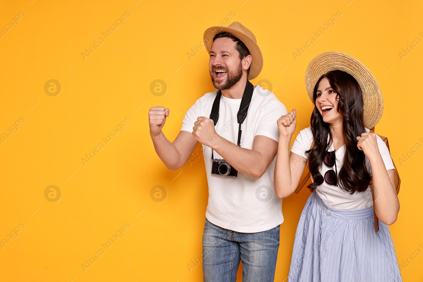 Photo of Tourism. Emotional couple in hats with camera on yellow background, space for text