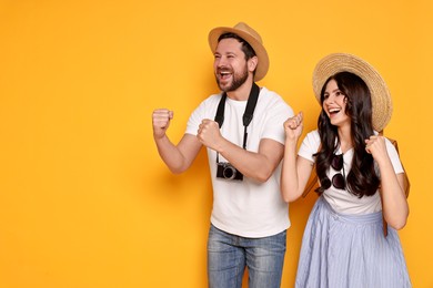 Tourism. Emotional couple in hats with camera on yellow background, space for text