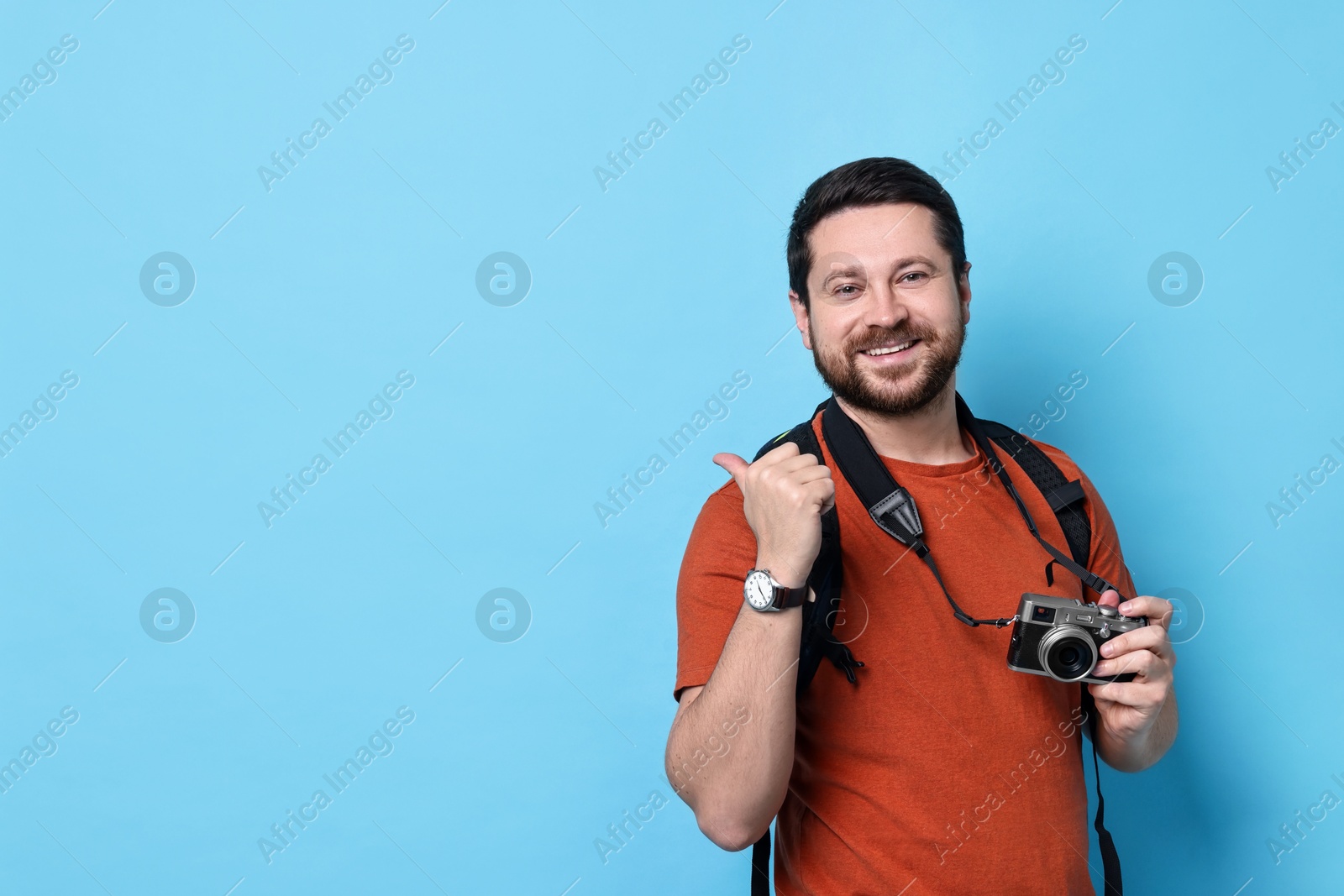 Photo of Traveller with vintage camera on light blue background, space for text