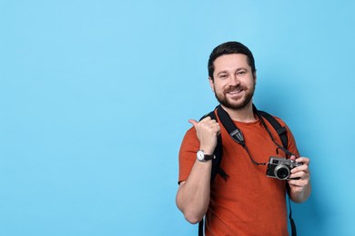 Traveller with vintage camera on light blue background, space for text