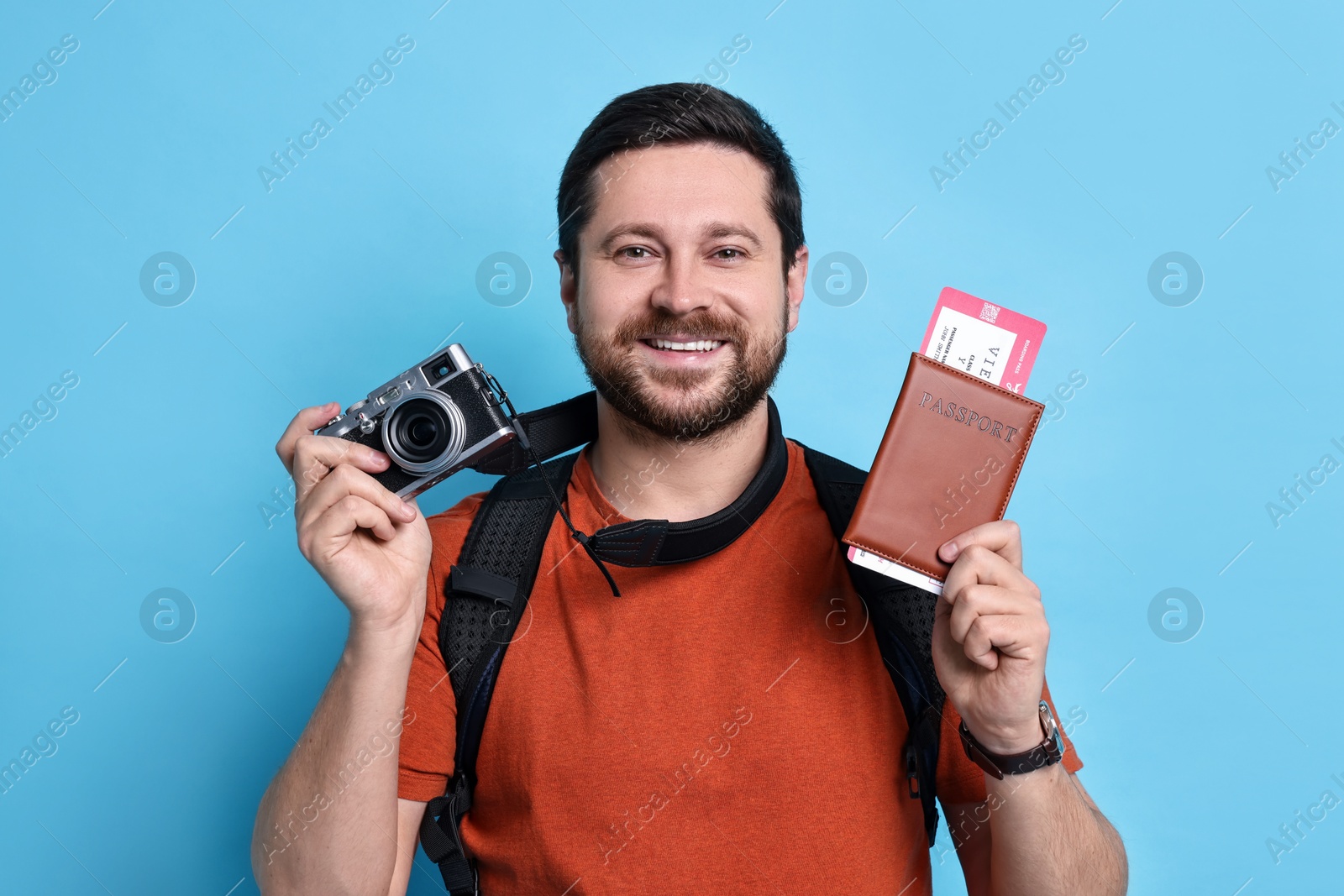 Photo of Traveller with vintage camera, passport and ticket on light blue background