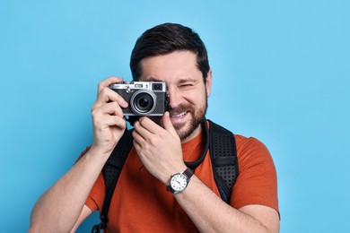 Traveller with vintage camera on light blue background