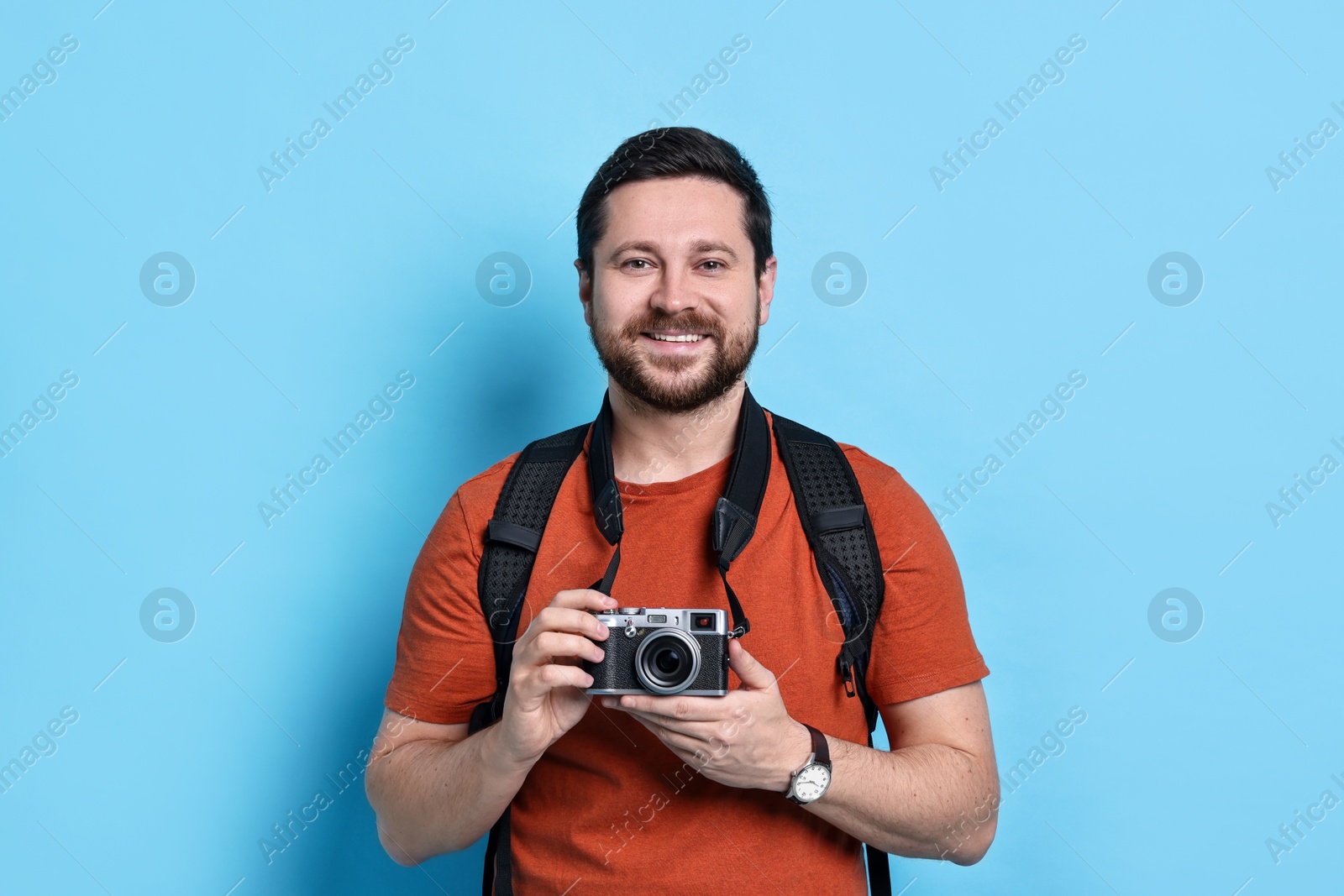 Photo of Traveller with vintage camera on light blue background