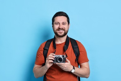 Photo of Traveller with vintage camera on light blue background