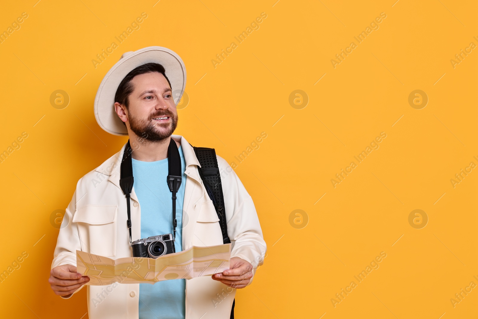 Photo of Traveller with vintage camera and map on orange background, space for text