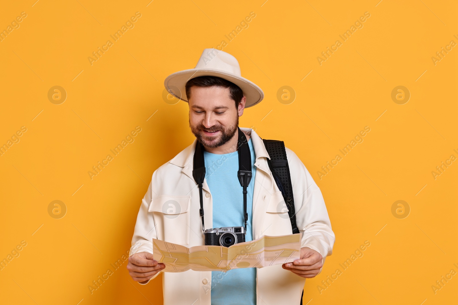 Photo of Traveller with vintage camera and map on orange background