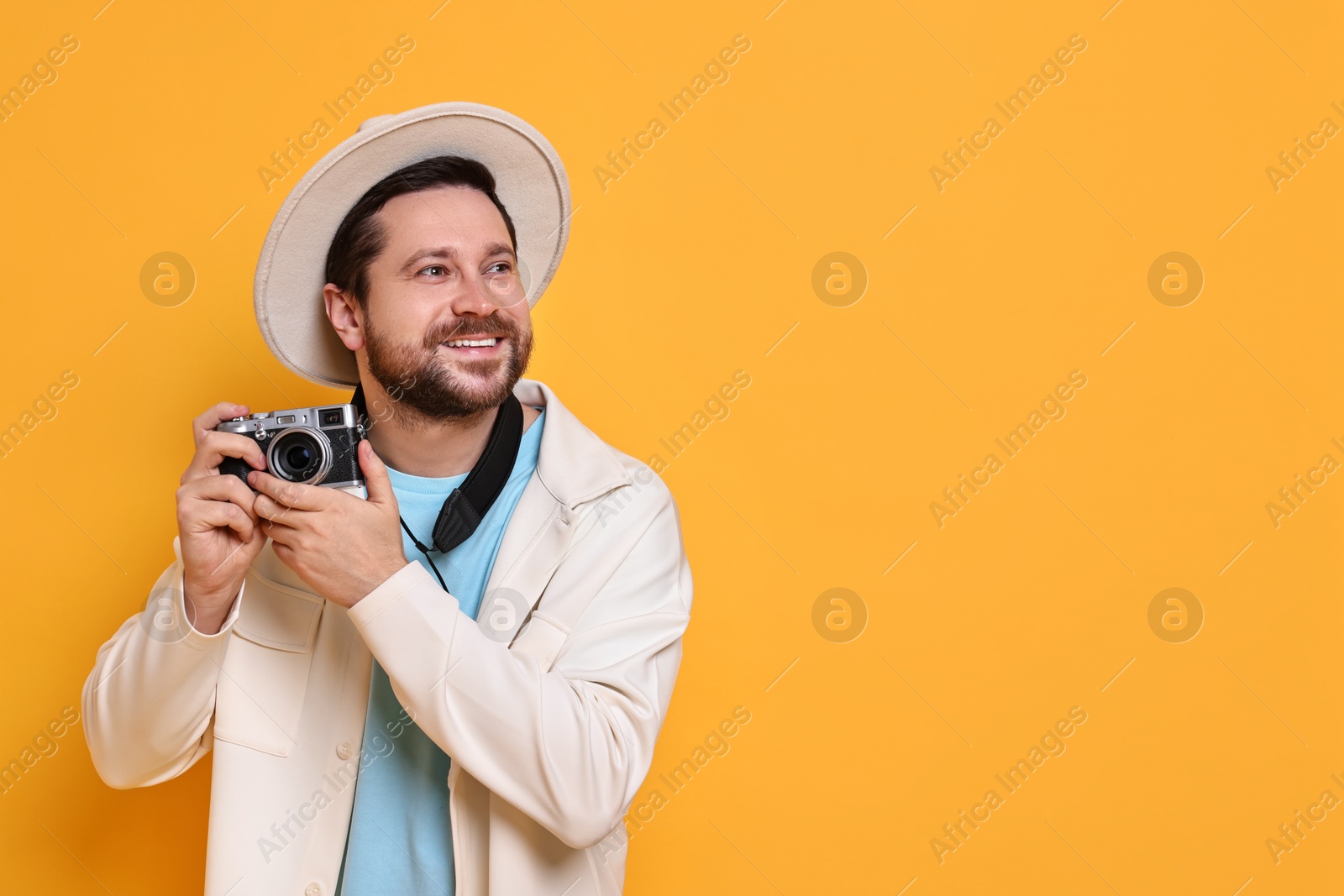 Photo of Traveller with vintage camera on orange background, space for text