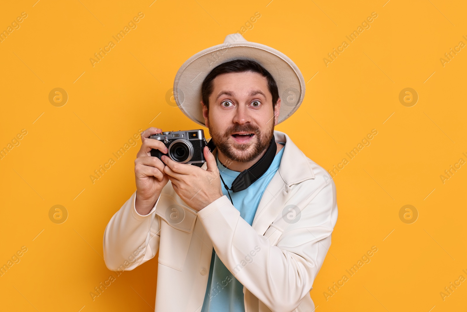 Photo of Traveller with vintage camera on orange background