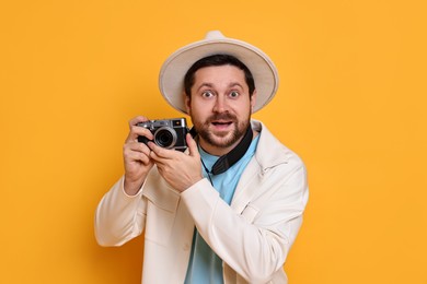 Traveller with vintage camera on orange background