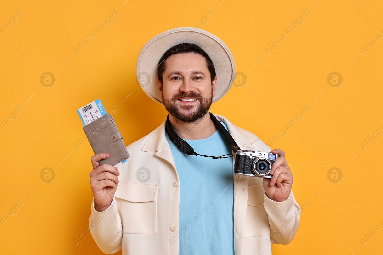 Photo of Traveller with vintage camera, passport and ticket on orange background