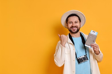 Traveller with vintage camera, passport and ticket on orange background, space for text