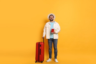 Photo of Traveller with suitcase, passport, map and ticket on orange background