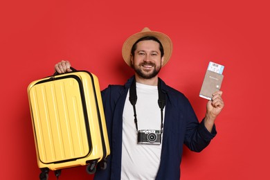 Photo of Traveller with suitcase, passport and ticket on red background