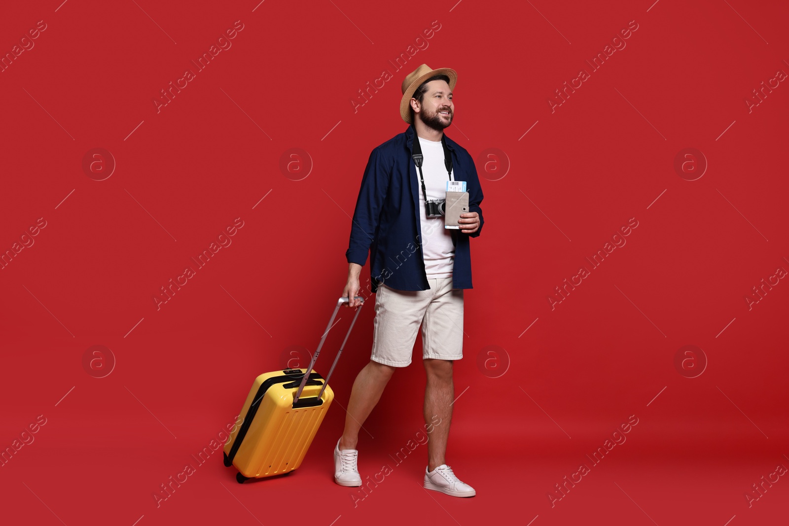 Photo of Traveller with suitcase, passport and ticket on red background