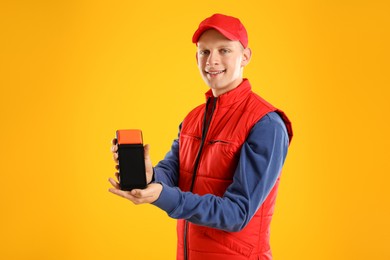 Photo of Happy courier with payment terminal on yellow background