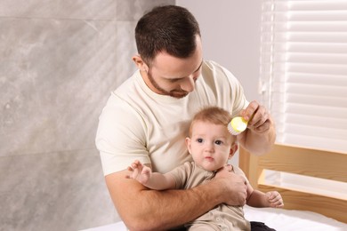 Man brushing hair of his little baby on bed indoors