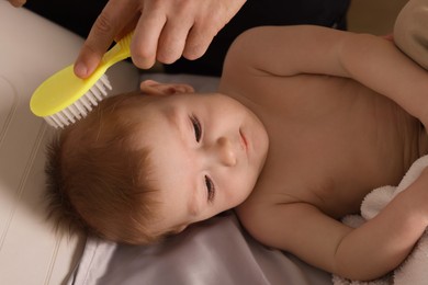 Photo of Man brushing hair of his little baby indoors, closeup